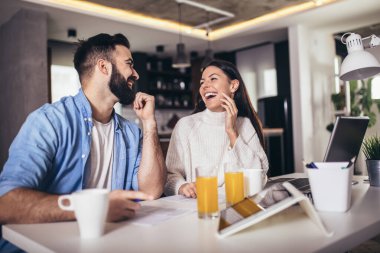 Evde çalışan genç çift dizüstü bilgisayar ve dijital tablet kullanıyor.