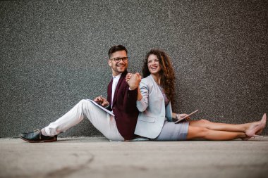 Genç iş adamları modern bir ofis binasının önünde oturuyorlar. 