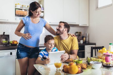 Hamile bir kadın kocası ve çocuğuyla kahvaltı yapar.