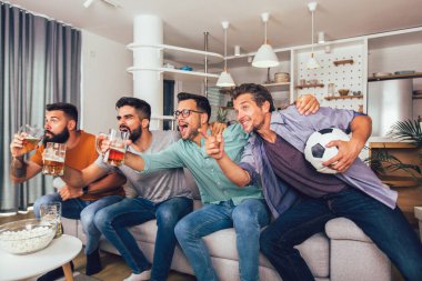 Mutlu erkek arkadaşlar ya da futbol taraftarları televizyonda futbol izleyip zaferi evde kutluyorlar..