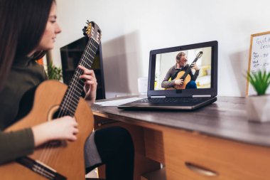 Bilgisayarla gitar çalan kız, çevrimiçi kursla çalmayı öğren