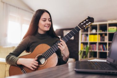 Bilgisayarla gitar çalan kız, çevrimiçi kursla çalmayı öğren