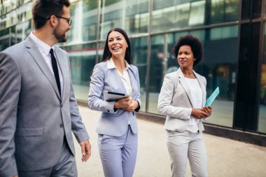 Dışarıda yürürken birbirleriyle konuşan üç genç iş adamı..
