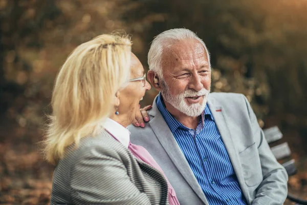 高齢者のカップルで聴覚障害がベンチの屋外に座って — ストック写真