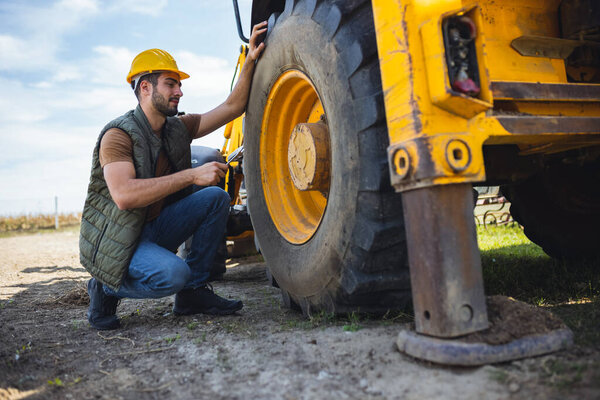 Экскаватор фиксирует шины на строительной площадке