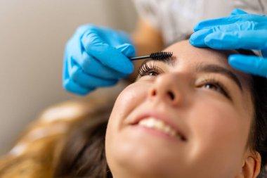 Genç bayan müşteri, temiz ve modern bir güzellik salonunda profesyonel kaş kaplaması (cerrahi olmayan kaş gerdirme olarak da bilinir) yaptırıyor..