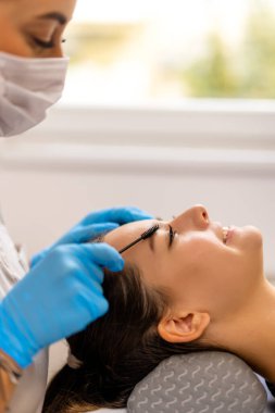 Genç bayan müşteri, temiz ve modern bir güzellik salonunda profesyonel kaş kaplaması (cerrahi olmayan kaş gerdirme olarak da bilinir) yaptırıyor..