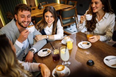 Tarz sahibi arkadaşlar restoranda içki içerken mutlu bir çift kucaklaşır. Zarif kıyafetler, kahve ve meyve suyu, kahkahalar ve çekilen neşeli sosyal anlar..