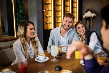 Tarz sahibi arkadaşlar restoranda içki içerken mutlu bir çift kucaklaşır. Zarif kıyafetler, kahve ve meyve suyu, kahkahalar ve çekilen neşeli sosyal anlar..