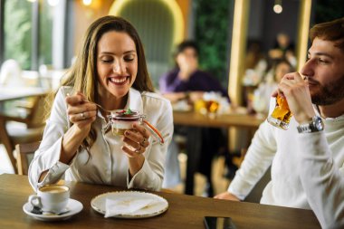 Bir çift bir restoranda pasta yer, birlikte anın tadını çıkarırlar. Sıcak, neşeli ve eğlenceli bir atmosfer, şık bir yemek ortamında yakalanır..
