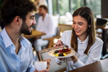 Bir çift bir restoranda pasta yer, birlikte anın tadını çıkarırlar. Sıcak, neşeli ve eğlenceli bir atmosfer, şık bir yemek ortamında yakalanır..