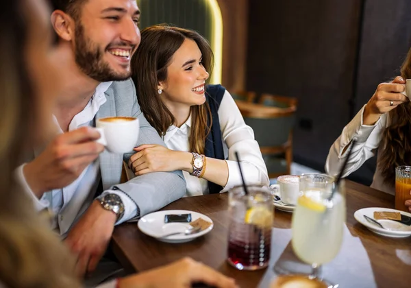 Tarz sahibi arkadaşlar restoranda içki içerken mutlu bir çift kucaklaşır. Zarif kıyafetler, kahve ve meyve suyu, kahkahalar ve çekilen neşeli sosyal anlar..