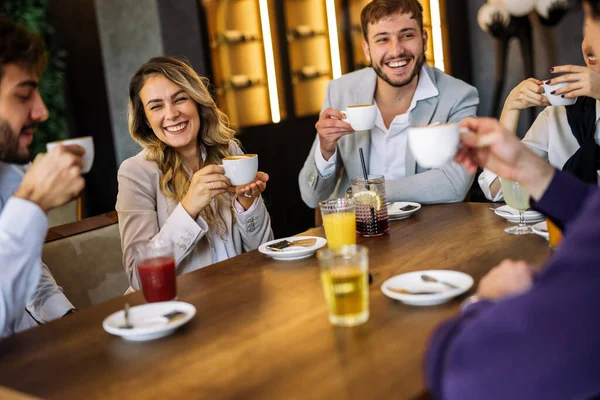 Bir grup şık arkadaş bir restoranda sohbet ediyor ve gülüyor kahve ve meyve suyu yudumluyor, zarif atmosferin ve hareketli sosyal anların tadını çıkarıyor..