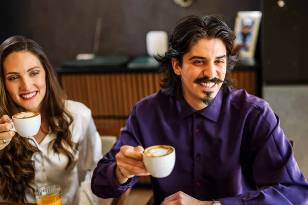 Bir grup şık arkadaş bir restoranda sohbet ediyor ve gülüyor kahve ve meyve suyu yudumluyor, zarif atmosferin ve hareketli sosyal anların tadını çıkarıyor..