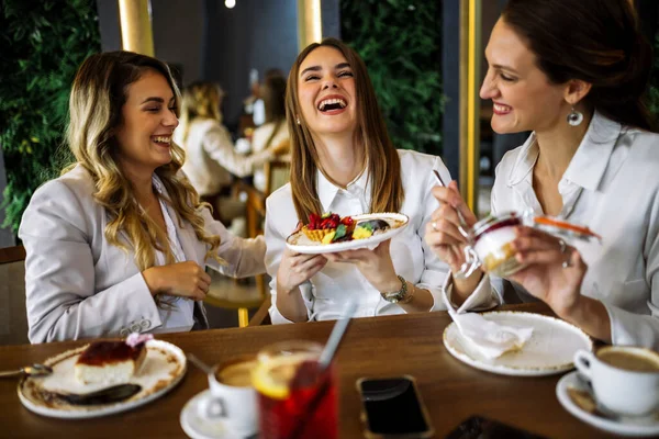 Üç kadın alışveriş yaptıktan sonra bir restoranda oturup pasta tadıyor. Eğlence, arkadaşlık, kahkaha ve şık bir atmosferde yakalanmış samimi sosyal anlar..