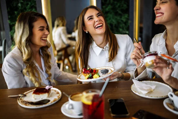 Üç kadın alışveriş yaptıktan sonra bir restoranda oturup pasta tadıyor. Eğlence, arkadaşlık, kahkaha ve şık bir atmosferde yakalanmış samimi sosyal anlar..