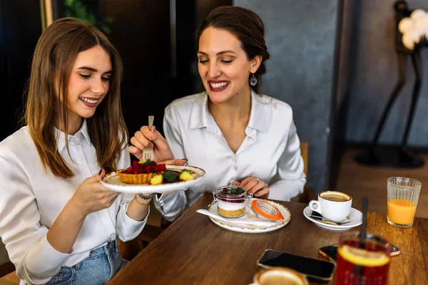 Üç kadın alışveriş yaptıktan sonra bir restoranda oturup pasta tadıyor. Eğlence, arkadaşlık, kahkaha ve şık bir atmosferde yakalanmış samimi sosyal anlar..