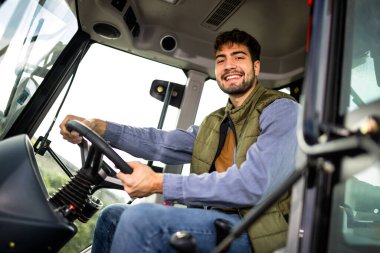 Kamyon kabininde oturan genç profesyonel kamyon şoförü, yoldaki aracı kullanmaya ve çalıştırmaya hazır..
