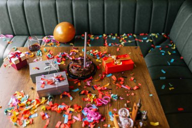 Konfeti, pasta ve hediyelerle kaplı dağınık masa ve kanepe. Yeni yıl, doğum günü ve kutlama partisinden kaotik bir sabah sahnesi..