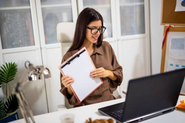 Çevrimiçi bir toplantıda meslektaşlarına grafik ve slayt sunan genç profesyonel bir kadın modern bir ofiste takım çalışması ve üretkenlik gösteriyor..