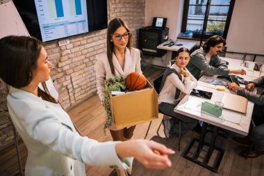 Ofisten çıkan genç bir bayan profesyonel, kişisel eşyalarını bir kutuda taşıyor, üzgün ve mağlup görünüyor, menajeri tarafından denetleniyor, işyeri çatışması ve profesyonel duygular gösteriyor..