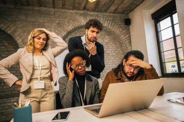 Bir konferans odasında dizüstü bilgisayarı incelerken endişeli görünen farklı ırklardan bir grup genç iş adamı, zorlukları tartışıyor ve bir takım olarak problem çözmeyi tartışıyorlar..