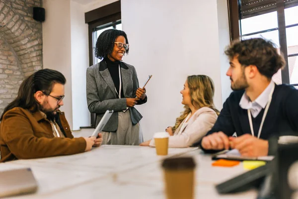Bir konferans salonunda toplanan, strateji ve fikirleri, çeşitliliği, takım çalışmasını ve modern kurumsal işbirliğini vurgulayan bir grup farklı ırktan genç iş adamı..