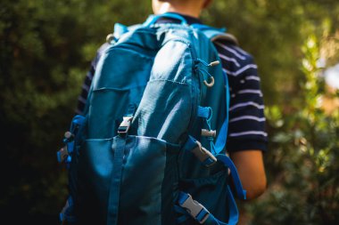 Genç bir çocuk yazın bir sırt çantasıyla yürüyüşe çıkıyor. Açık hava macerası, özgürlük ve gençlik keşfi, seyahat, yaşam tarzı ve doğa temalı içerik için ideal.