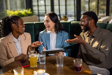 İş adamları kahve dükkanında toplantı yapıyor. Kahve dükkanında bir masada oturan iş adamları, konuşup gülüyorlar..