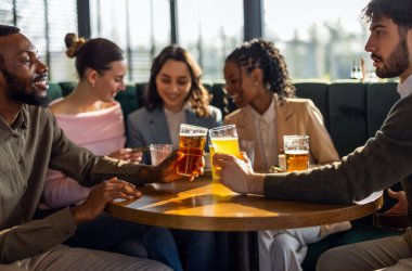Bir restoranda bira içip eğlenen mutlu bir arkadaş grubu. Sıcak bir sosyal ortamda gülüp rahatlıyorlar..