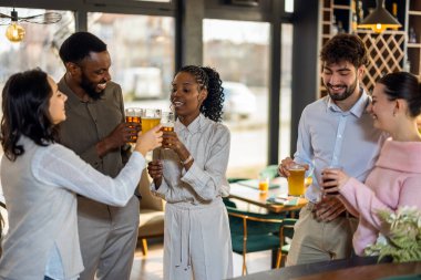 Bar tezgahında çok ırklı arkadaşlar, bira içip sohbet ediyorlar. Sosyalleşme, dostluk ve rahat, rahat bir atmosfer gösteriyorlar..