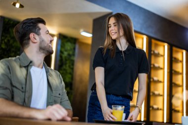 Dost canlısı garson kafede genç bir adama kahve ve meyve suyu ikram ediyor..