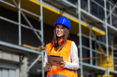 İş yerindeki dijital tabletin inşaat planlarını kontrol eden kadın inşaat mühendisi.