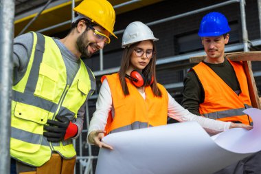 İnşaat alanının planlarına bakan üç mühendis ekibi.