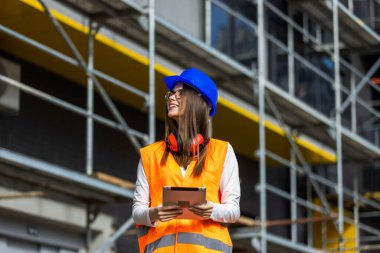 İnşaat alanında dijital tablet kullanan genç bir inşaat işçisi..