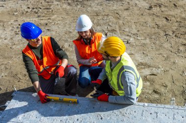 İnşaat alanında projeyi tartışan üç mühendisin üst görünümü