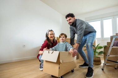 Neşeli genç bir aile, yeni bir dairede ilk günlerinin tadını çıkarırken, ebeveynler çocuklarını bir kutunun içinde yere seriyorlar..