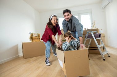 Neşeli bir çift ve yeni yürümeye başlayan çocukları, parlak, ferah bir odada bir sürü karton kutu arasında taşınma gününü kutluyorlar..