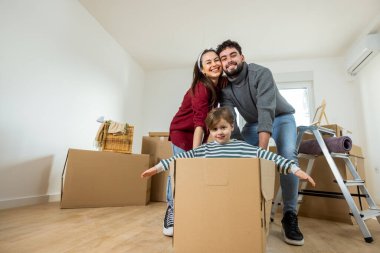 Neşeli genç bir aile, yeni bir dairede ilk günlerinin tadını çıkarırken, ebeveynler çocuklarını bir kutunun içinde yere seriyorlar..