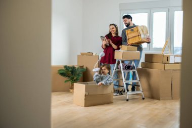 Yeni evlerinin zemininde oturan genç bir çift, çocukları içeride oynarken taşınan bir kutuda bulunan eski fotoğrafları hatırlıyorlar..