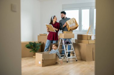 Yeni evlerinin zemininde oturan genç bir çift, çocukları içeride oynarken taşınan bir kutuda bulunan eski fotoğrafları hatırlıyorlar..