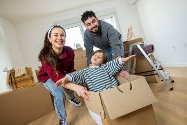 Neşeli genç bir aile, yeni bir dairede ilk günlerinin tadını çıkarırken, ebeveynler çocuklarını bir kutunun içinde yere seriyorlar..
