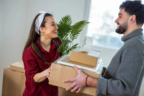 Neşeli bir adam ve kadın ellerinde karton kutularla birbirlerine bakıp gülüyorlar ve ilk dairelerine taşınmalarının heyecanını kutluyorlar..