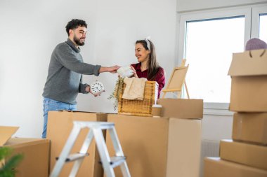 Karton kutuların arasında durup şık bir duvar saatine bakan kadın ve erkek yeni yaşam alanları için bavullarını boşalttılar..