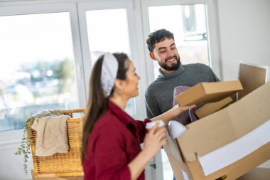 Kadın ve erkek birlikte çalışarak taşınan birçok kutunun arasında boş bir odaya yerleşiyorlar..