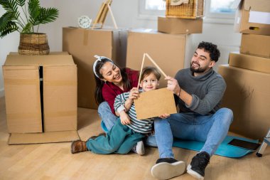 Yerde, taşınan kutuların arasında oturan genç bir çift sembolik olarak vardiyalı çatısı olan küçük çocuklarını koruyorlar. Bu güçlü kavramsal imaj ev sigortası, ipotek hizmetleri ve aile bankacılığı reklamları için mükemmeldir..