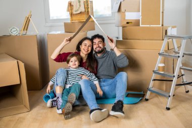 Genç bir aile yeni boş dairelerinde taşınan bir kutuyla sembolik bir barınak oluşturuyor..