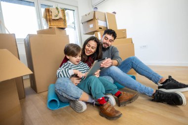 Tablet ekranına gülümseyen mutlu bir anne, baba ve oğlun yürek ısıtan kavramsal görüntüsü. Aşkı, bağlılığı, birliği ve teknolojinin kusursuz bütünlüğünü temsil eder..