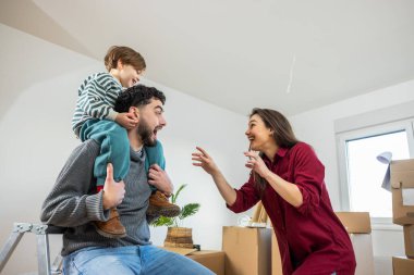 Neşeli bir baba oğlunu omuzlarında taşırken anne çocuğu komik bir ifadeyle güldürmek için ona katılır. Paketlenmemiş eşyalarla çevrili bir ailenin birlikte yeni bir sayfa açmasının heyecanını, bağlantısını ve neşesini sembolize ediyor.