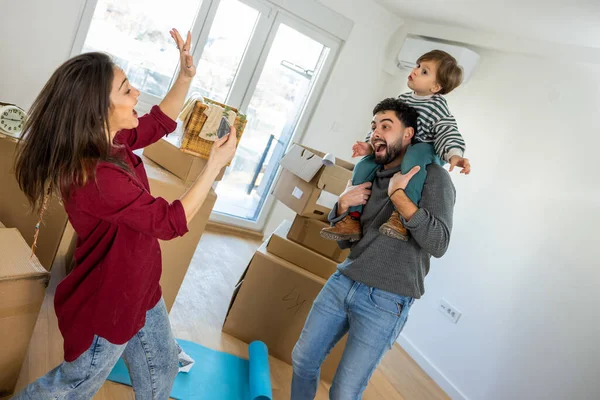 Taşınırken neşeli bir çocuğun babasının omuzlarına oturduğu, annesinin akıllı telefonuyla fotoğraf çekerken güldüğü samimi bir an. Etrafı karton kutularla çevrili yeni dairelerinde yeni bir başlangıcın saf eğlence ve heyecanını yakalıyorlar.